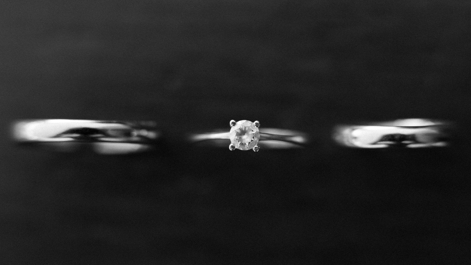 Anillos de boda de plata con diamante central, sobre fondo negro, mostrando la elegancia de la joyería nupcial.