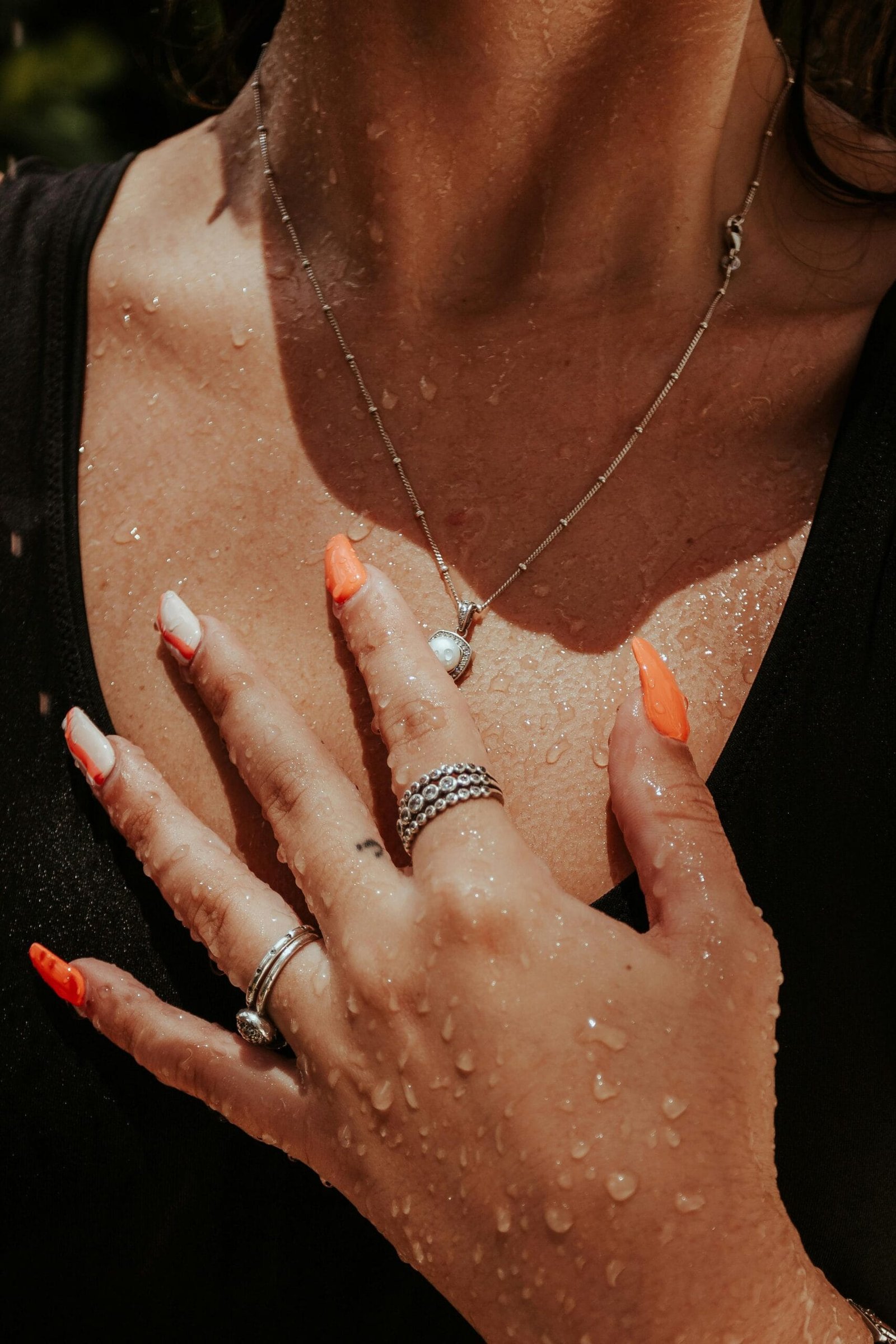 Mujer portando un conjunto de collar y anillos de plata con un aspecto sofisticado y fresco.