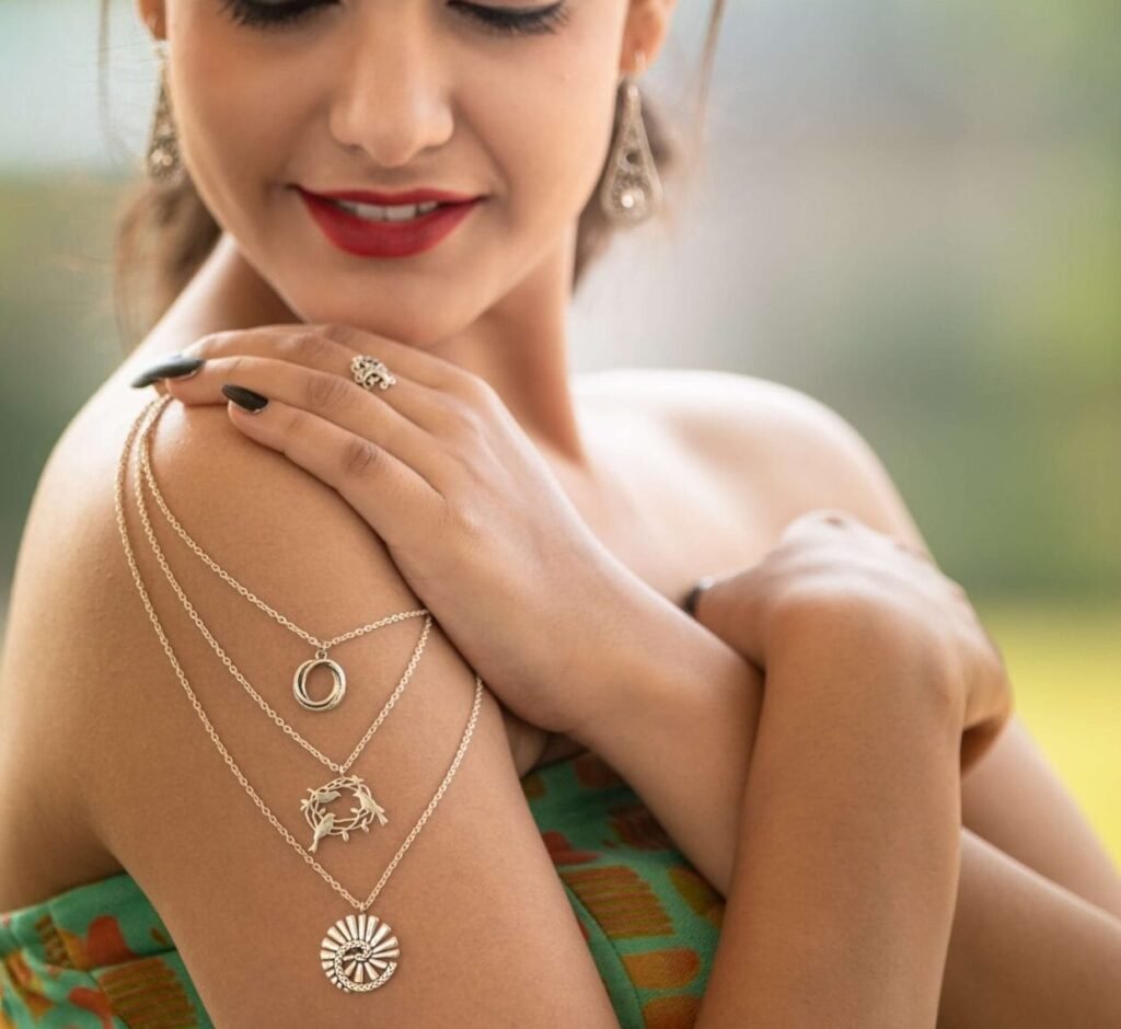 Mujer de piel morena muestra collares de plata fina brillante con dijes o colgantes elegantes de distintas figuras con cadenas de calidad