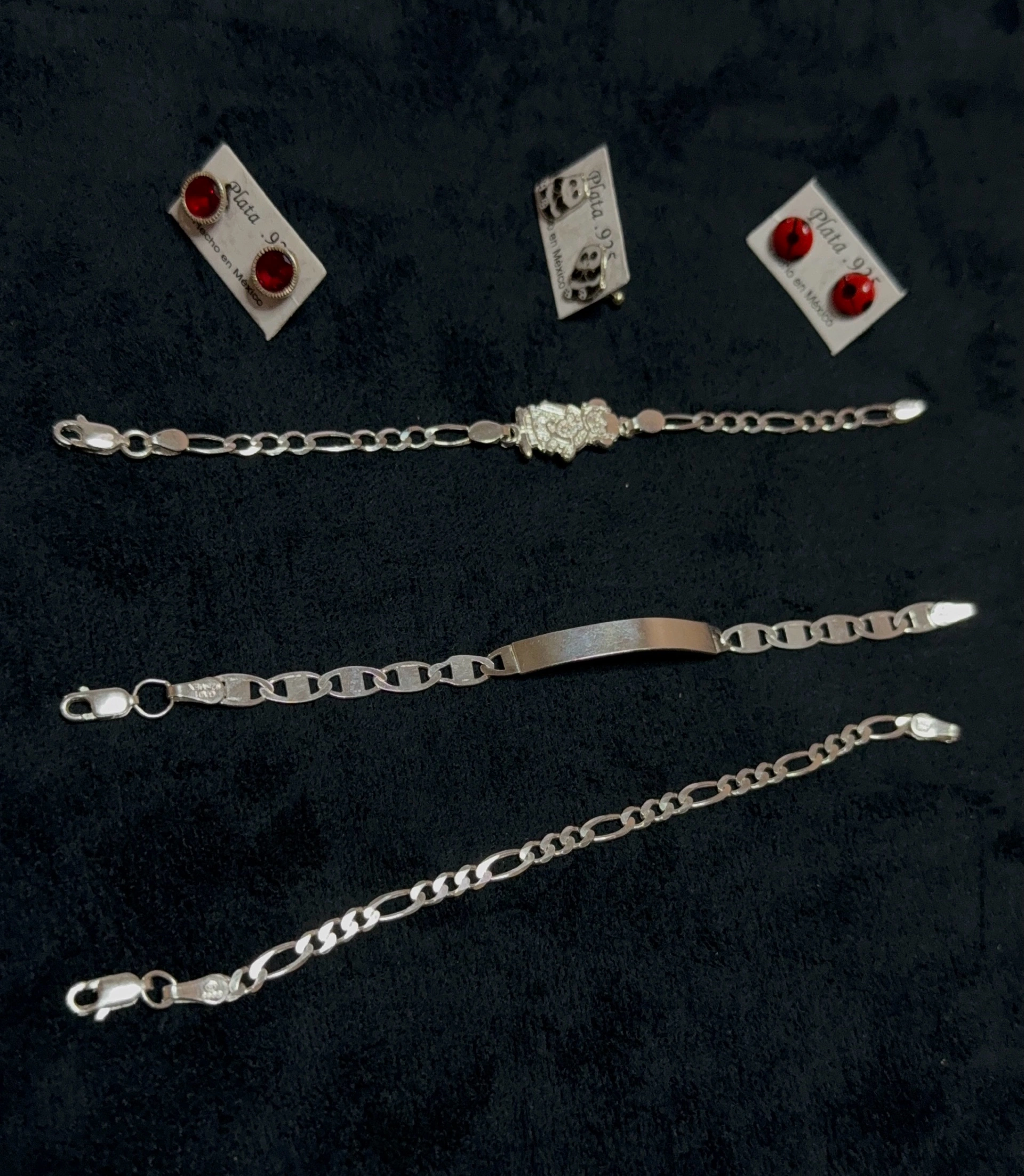 Pulseras de plata 925 para niños con placa para grabar y aretes de piedra roja, joyería infantil, sobre terciopelo azul marino.